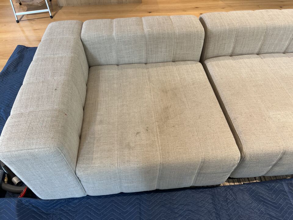 Cream modular sofa left seat and arm with visible small dark marks before upholstery cleaning