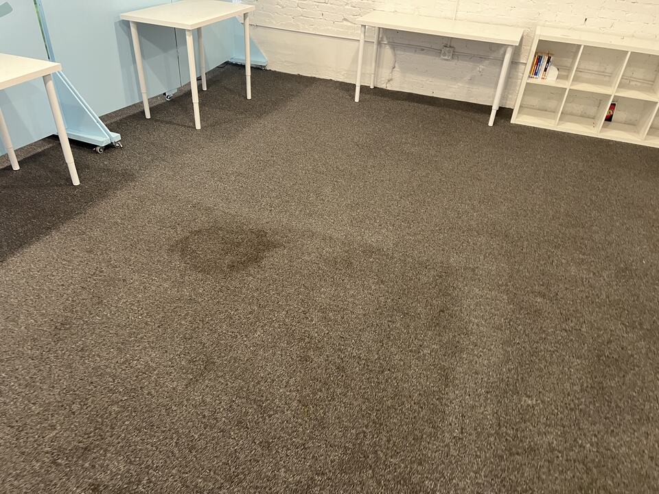 Visible carpet staining near tables and a pale-blue partition