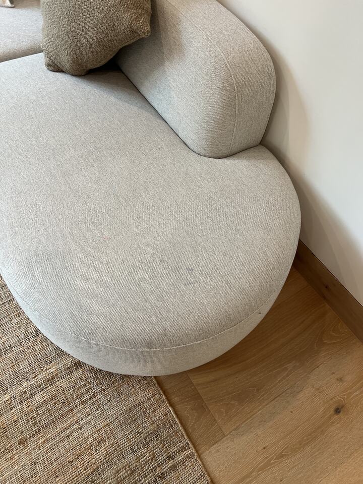 A rounded upholstered chair beside a patterned rug