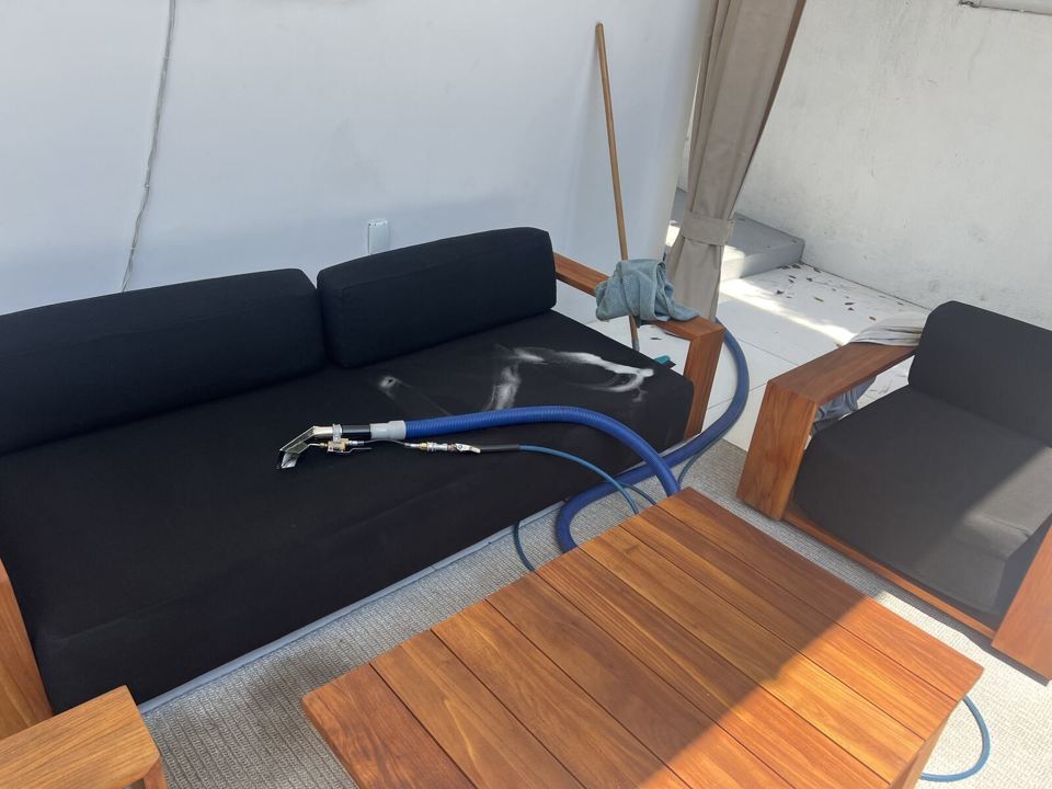 An upholstery cleaning tool working on a sofa